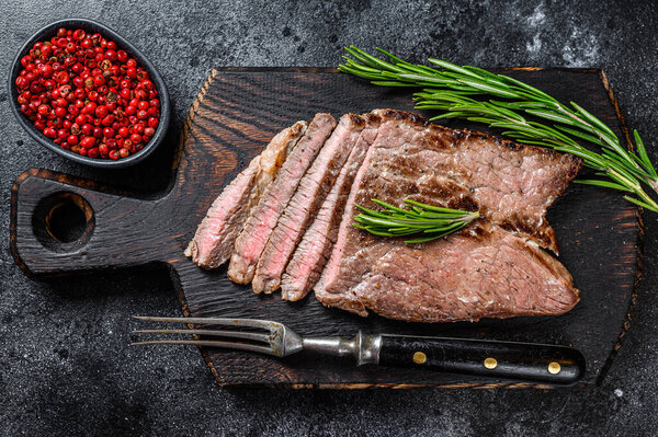 Grilled veal meat chop steak on a cutting board. Black background. Top view.