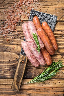 Bir kasap satırının üzerinde çiğ domuz eti ve sığır eti sosisi. Ahşap arka plan. Üst Görünüm