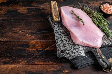 Tahta bir kasap tahtasında et satırıyla çiğ hindi göğsü fileto. Koyu ahşap arka plan. Üst Manzara. Boşluğu kopyala