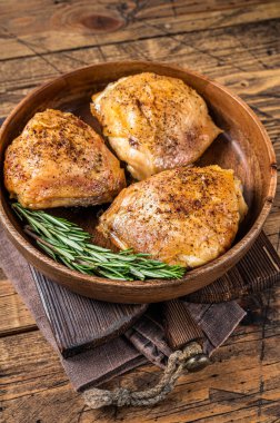 Biberiye ve bitkilerle birlikte ahşap bir tabakta kızarmış tavuk butları. Ahşap arka plan. Üst Görünüm