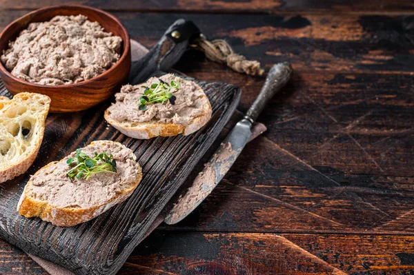 Toast met eendenpaté Rillettes de Canard op houten plank. Donker houten achtergrond. Bovenaanzicht. Kopieerruimte — Stockfoto