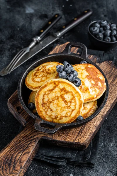 Pancake dengan blueberry segar dan sirup maple dalam panci. Latar belakang hitam Tampilan Atas — Stok Foto