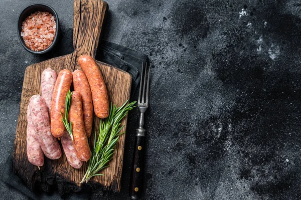 Неприготовані ковбаски з соусом Chorizo і Bratwurst з спеціями на дерев'яній дошці. Чорний фон. Вид зверху. Копіювальний простір — стокове фото