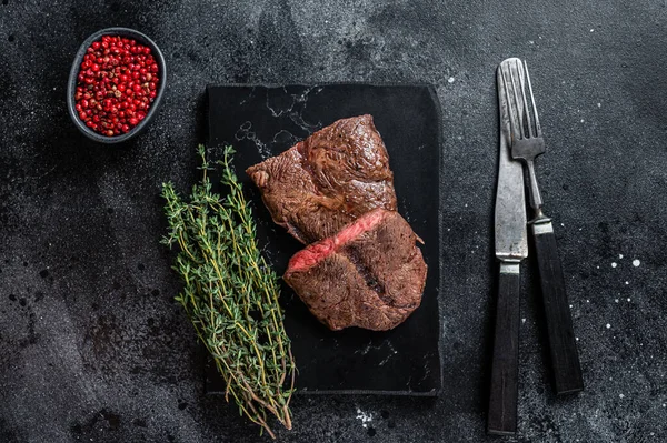 Grillé Top Blade ou plat steaks de viande de rôti de bœuf en fer sur panneau de marbre. Fond noir. Vue du dessus — Photo