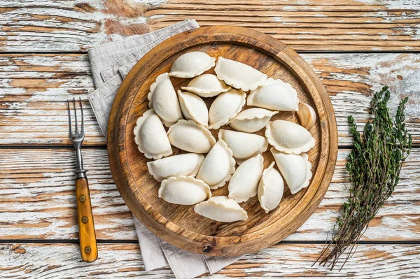 Hemlagade råa frysta dumplings, vareniki, pierogi fyllda med potatis på en träskiva. Vit trä bakgrund. Ovanifrån — Stockfoto