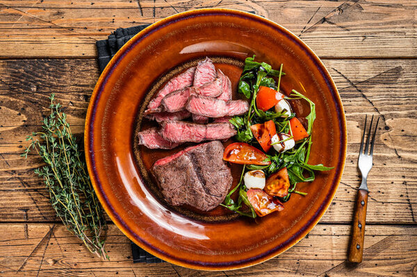 BBq roasted Oyster Top Blade or flat iron roast beef meat steak on a plate with salad. Wooden background. Top View