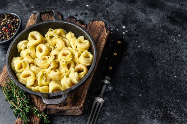 Tavada peynir soslu İtalyan tortellini makarnası. Siyah arka plan. Üst Manzara. Boşluğu kopyala