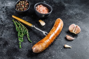 Et çatalında baharat ve otlarla kızartılmış sosis ızgarası. Üst Manzara. Siyah arkaplan