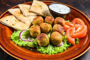 Pita ekmeği, taze sebze ve soslu vejetaryen falafel. Karanlık arka plan. Üst görünüm