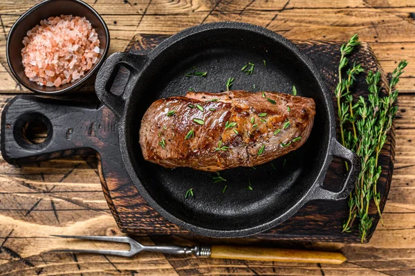 Filete de carne de cordero frito en una sartén. fondo de madera. Vista superior —  Fotos de Stock