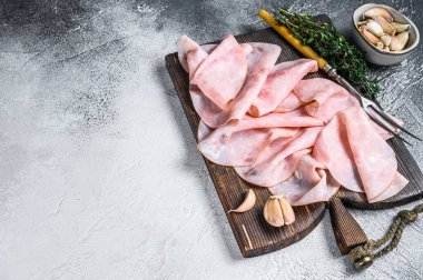 İnce jambonlu ahşap kesim tahtasında otlarla dilimlenmiş. Beyaz arka plan. Üst Manzara. Boşluğu kopyala