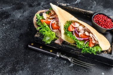 Ahşap tepside pide ekmeğin içinde ızgara tavuk eti ve sebzeli çörek. Siyah arka plan. Üst Manzara. Boşluğu kopyala