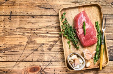 Ahşap tepside otlu çiğ kuzu eti. Ahşap arka plan. Üst Manzara. Boşluğu kopyala