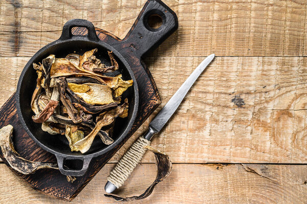 Mix of chopped wild dried mushrooms in a pan. wooden background. Top view. Copy space