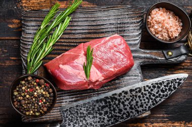 Tahta kesme tahtasının üzerinde çiğ kuzu eti ve şifalı otlar. Koyu ahşap arka plan. Üst görünüm