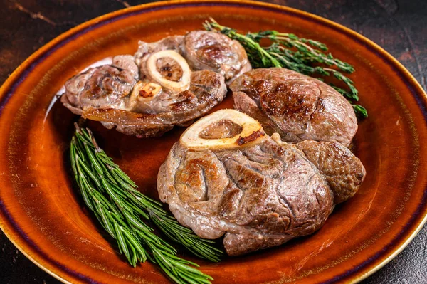 Kemikte pişmiş et, Osso Buco dana inciği, İtalyan ossobuco bifteği. Koyu ahşap arka plan. Üst görünüm