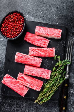 Yengeç surimi mermer tahtaya yapışıyor. Siyah arka plan. Üst görünüm