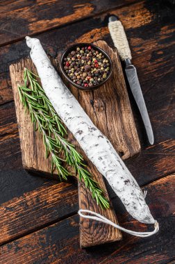 Tahta kesme tahtasının üzerinde İspanyol Fuet salamı sosisi. Koyu ahşap arka plan. Üst görünüm