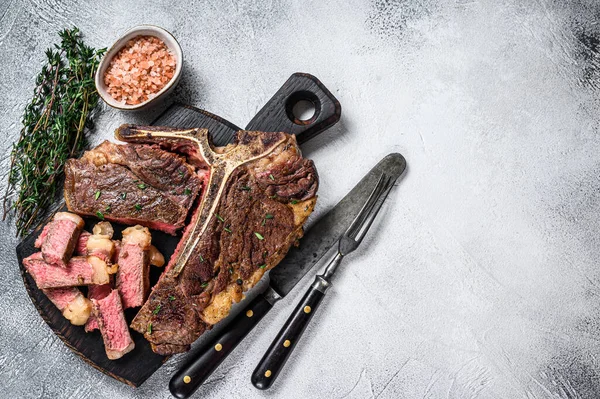 Gesneden gegrild vlees van T-bone rundvlees Biefstuk op een houten snijplank. Witte achtergrond. Bovenaanzicht. Kopieerruimte — Stockfoto