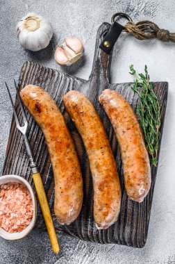 Ahşap kesme tahtasının üzerinde baharat ve otlarla kızartılmış sosisler. Üst Manzara. Beyaz arkaplan