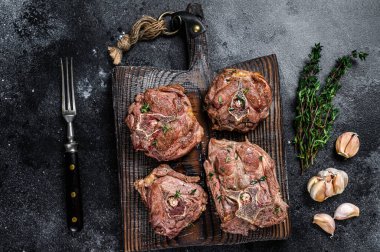 Ahşap bir tahtanın üzerinde ızgara kuzu eti ve otlar. Siyah arka plan. Üst görünüm