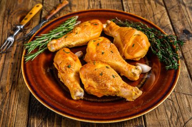 Kırsal bir tabakta taze tütsülenmiş tavuk budu ve otlar. Ahşap arka plan. Üst görünüm