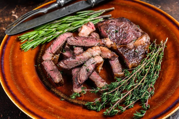 Filete de carne de res a la parrilla en rodajas o de costilla en un plato rústico. Fondo oscuro. Vista superior —  Fotos de Stock