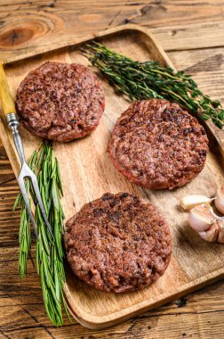 Barbekü ızgara biftek köfteleri, ahşap tepside kıyma. Ahşap arka plan. Üst görünüm