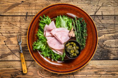 Taze salata ve kapari ile dilimlenmiş füme jambon. Ahşap arka plan. Üst görünüm