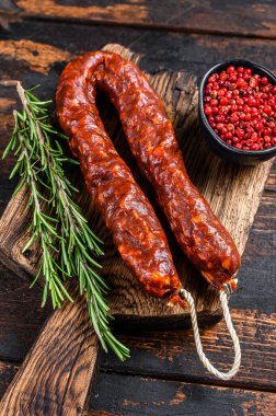 Chorizo domuz eti kurutulmuş et sosisi ahşap bir kesme tahtasında. Koyu ahşap arka plan. Üst görünüm