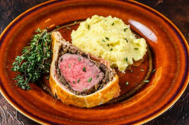 Köy tabaklarında patates püresi ile Wellington usulü biftek. Karanlık arka plan. Üst görünüm