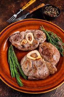 Kemikte pişmiş et, Osso Buco dana inciği, İtalyan ossobuco bifteği. Koyu ahşap arka plan. Üst görünüm