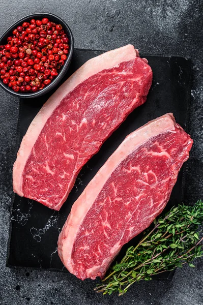 Syrový steak z krkovičky nebo hovězí steak z krkovičky na mramorové desce. Černé pozadí. Horní pohled — Stock fotografie