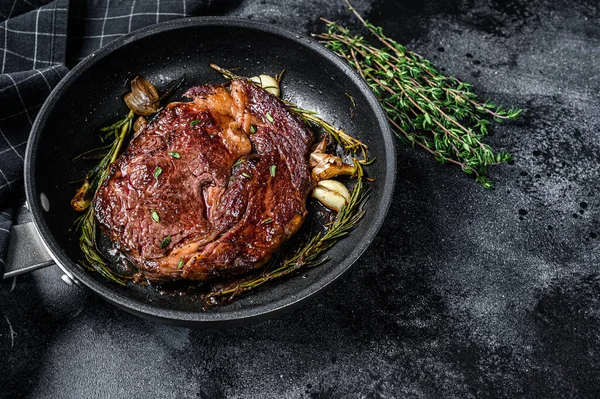 Filete de costilla asada, carne de res de costilla en una sartén. Fondo negro. Vista superior. Copiar espacio —  Fotos de Stock