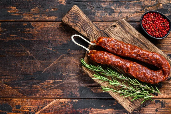 Chorizo wieprzowina suche peklowane mięso kiełbasa na drewnianej desce rozbioru. Ciemne drewniane tło. Widok góry. Przestrzeń kopiowania — Zdjęcie stockowe