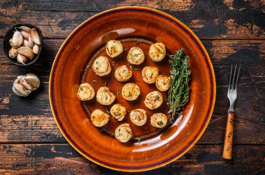 Tabakta tereyağlı baharat soslu kızarmış istiridye. Koyu ahşap arka plan. Üst görünüm