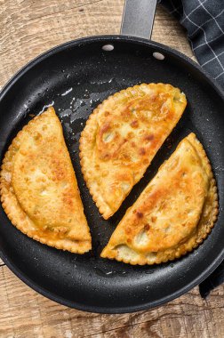 Etli ve otlu ev yapımı cheburekler, geleneksel Kafkas mutfağı. Ahşap arka plan. Üst görünüm