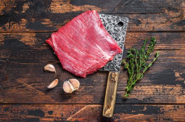 Satırın üzerinde çiğ et mermerden yapılmış biftek. Karanlık ahşap arka plan. Üst görünüm