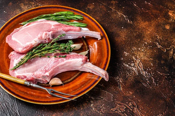 Çiğ domuz pirzolası, et bifteği, biber ve tuz. Karanlık arka plan. Üst Manzara. Boşluğu kopyala