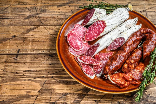 Charcuterie espagnole aux saucisses tranchées salami, fuet et chorizo sur une assiette rustique. fond en bois. Vue de dessus. Espace de copie — Photo