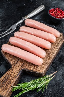 Biberiyeli ahşap bir tahtanın üzerinde taze çiğ tavuk ve hindi eti sosisi. Siyah arka plan. Üst görünüm