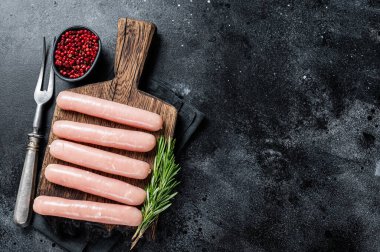 Biberiyeli ahşap bir tahtanın üzerinde taze çiğ tavuk ve hindi eti sosisi. Siyah arka plan. Üst Manzara. Boşluğu kopyala