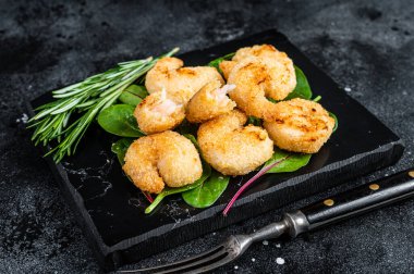 Misket tahtasında yeşil salatalı kızarmış karides karidesi. Siyah arka plan. Üst görünüm