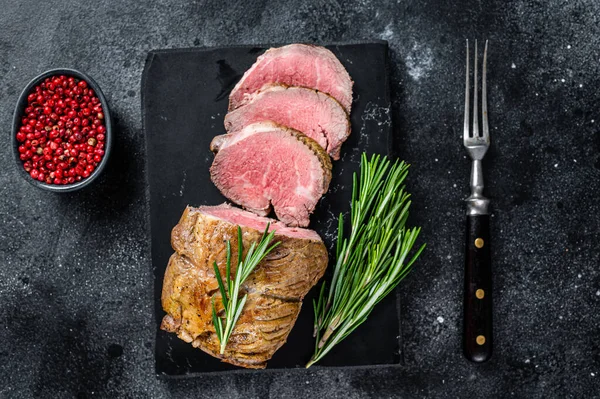 Filé de rosbife Carne de lombo em uma placa de mármore. Fundo preto. Vista superior — Fotografia de Stock