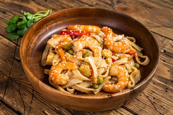 Udon roerbak noedels met garnalen in een houten kom. houten achtergrond. Bovenaanzicht — Stockfoto