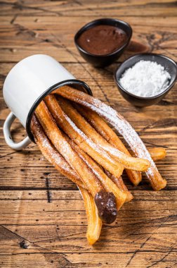 Şeker ve çikolata soslu Churros. Ahşap arka plan. Üst görünüm