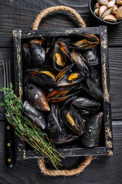 Kabuklu midyeler ahşap bir tepside otlarla birlikte. Siyah ahşap arka plan. Üst görünüm
