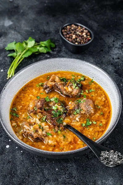 Zuppa di agnello Kharcho con carne di montone, riso, pomodori e spezie in una ciotola. Fondo nero. Vista dall'alto — Foto Stock