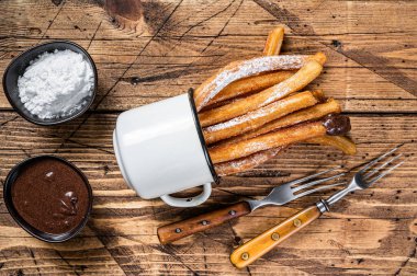 Şeker ve çikolata soslu Churros. Ahşap arka plan. Üst görünüm
