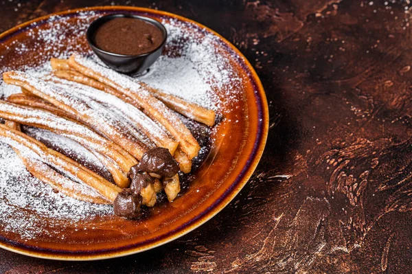 Churros de tapas españolas con salsa de azúcar y chocolate. Fondo oscuro. Vista superior. Copiar espacio — Foto de Stock